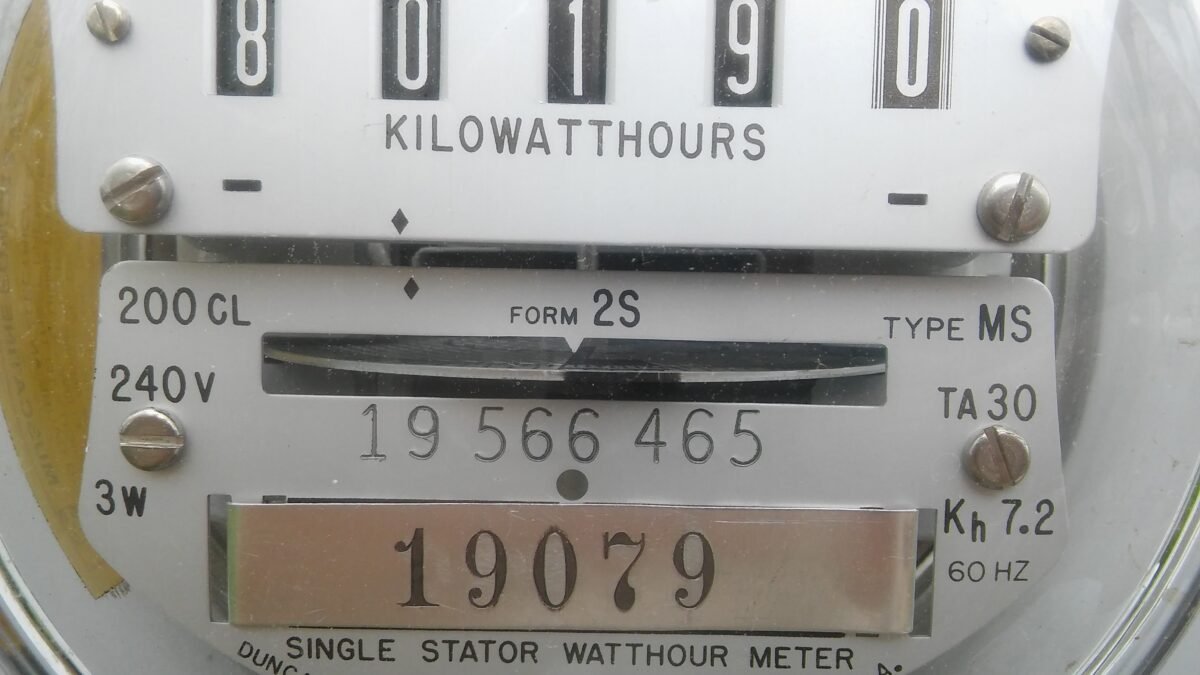Close-up em medidor analógico e digital de energia elétrica residencial registrando consumo em kWh.