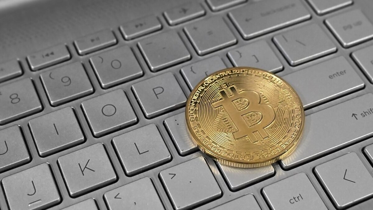 Moeda de Bitcoin sobre teclado de laptop em alerta de cibersegurança. Foto: Satheesh Sankaran / Wikimedia Commons