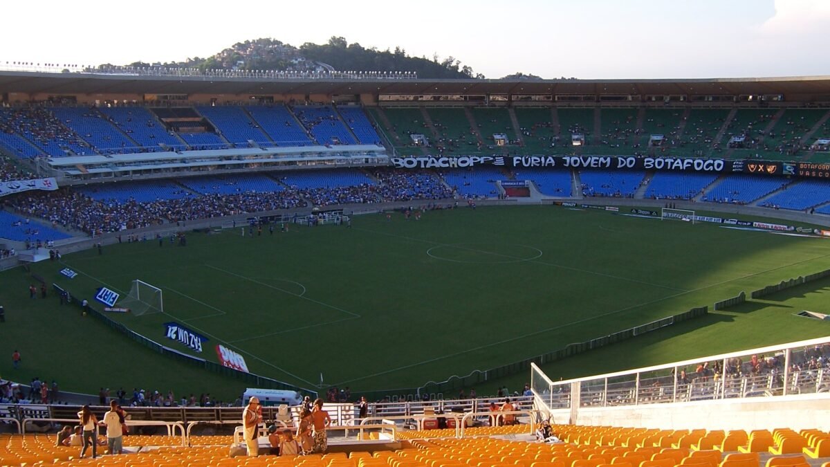 Arquibancadas do estádio lotadas por grande multidão de torcedores celebrando jogo de futebol.